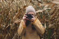 woman taking a picture wearing a yellow wool jumper